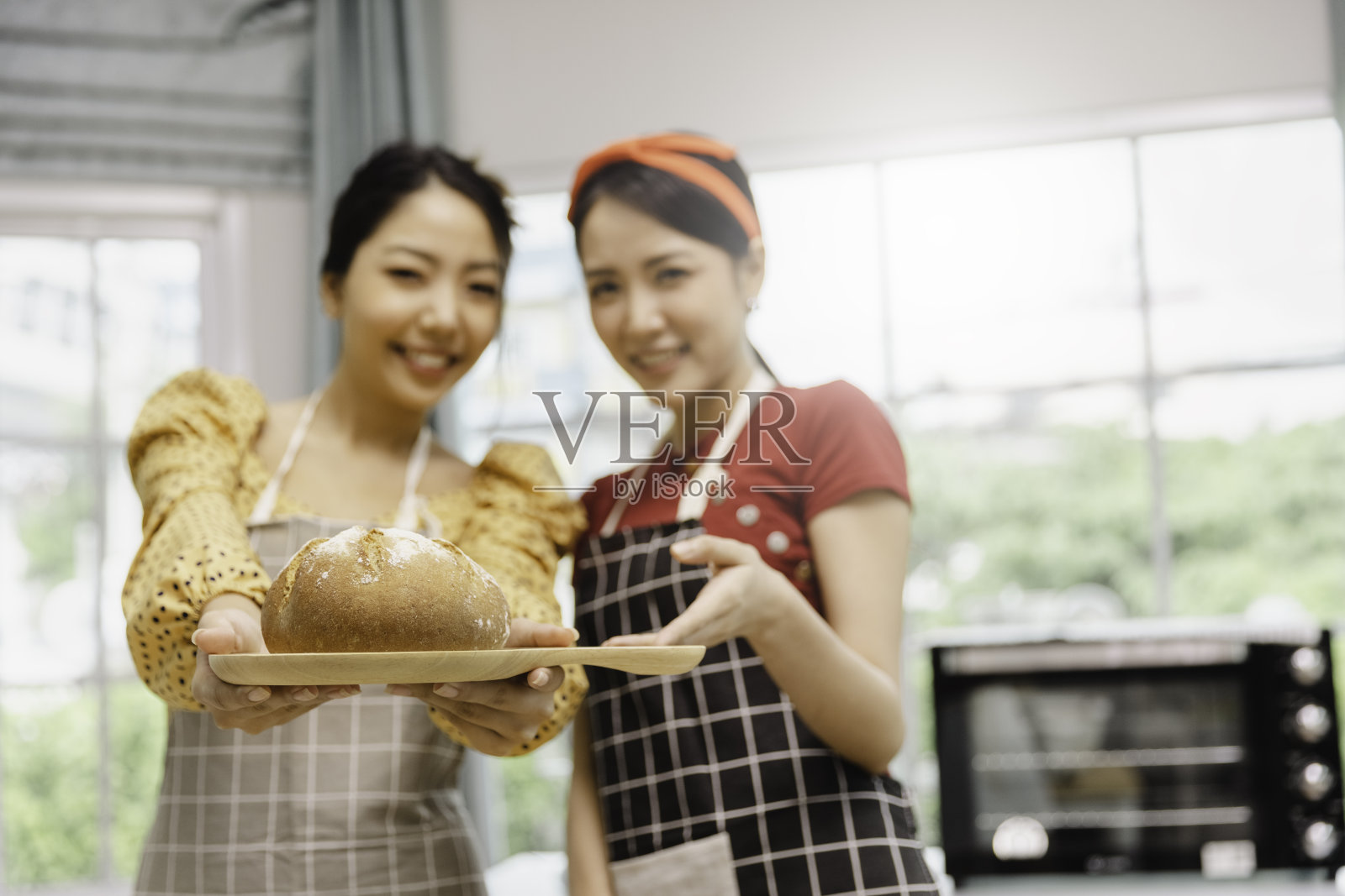 两个年轻的亚洲女性朋友制作烘焙面包，并使用摄像头录制或在线流媒体直播展示社交媒体、Vlogger或博主的小生意烹饪概念照片摄影图片