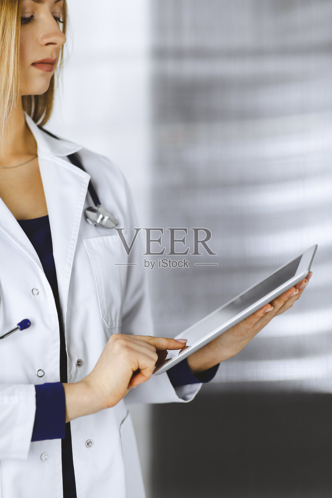 年轻的职业女医生站在诊所里，正在使用平板电脑。美丽的女医生在工作的肖像。完善的医院医疗服务。医学的概念照片摄影图片