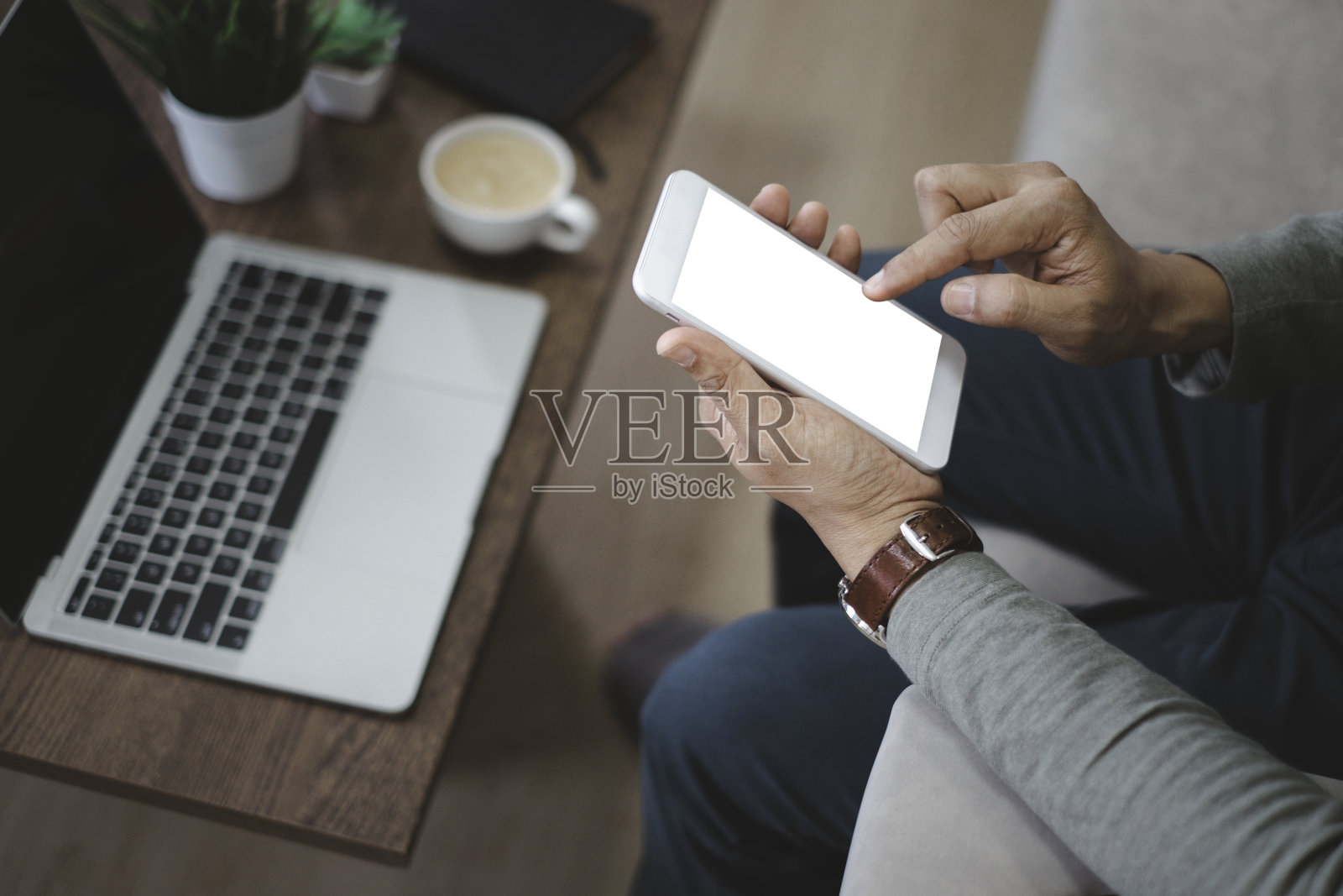 男人的手使用的图像，拿着智能手机或移动模型与空白的白色屏幕显示。照片摄影图片