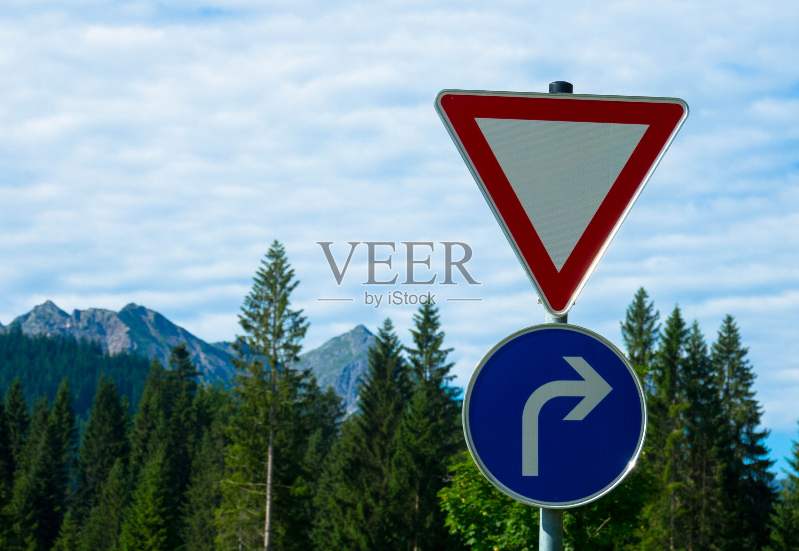 两个交通标志：红色倒三角标志和蓝色右转标志照片摄影图片