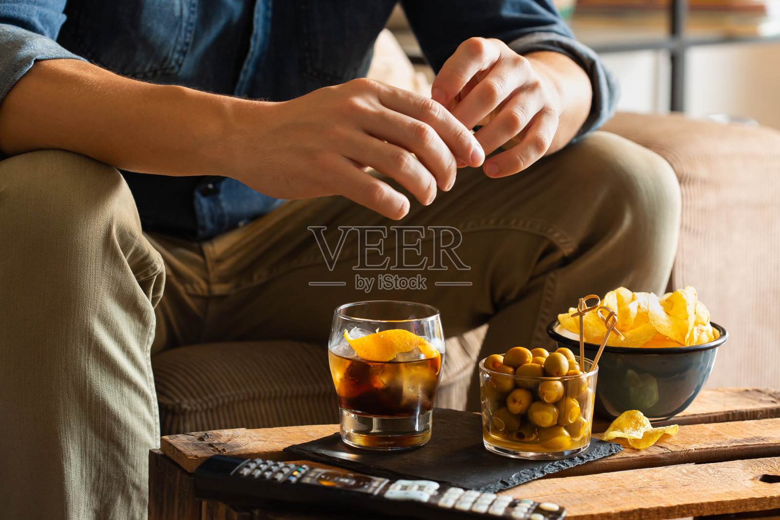 男人下班后在家喝苦艾酒吃零食照片摄影图片