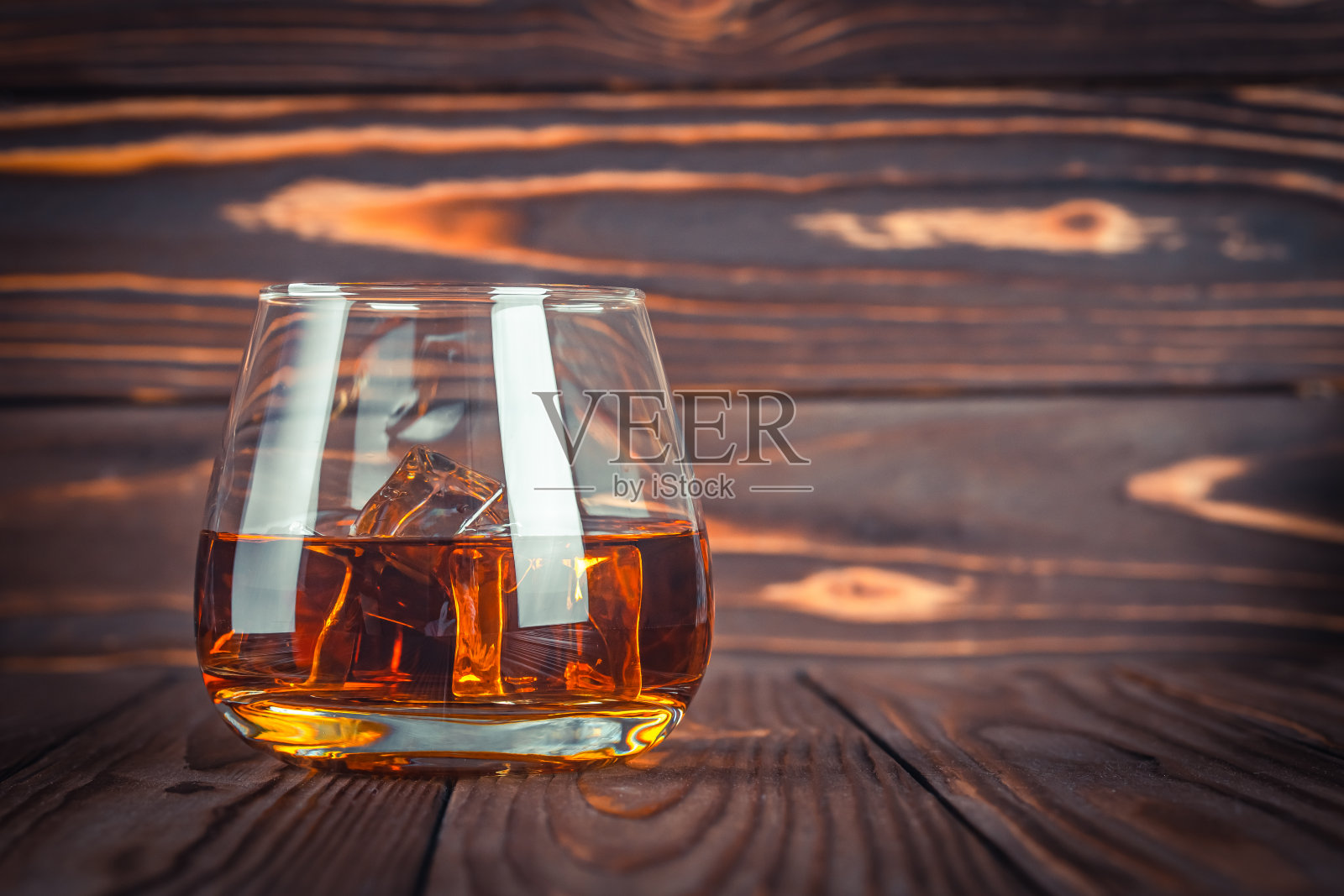 一杯加冰的威士忌，白兰地放在深棕色的木桌上。波本威士忌。烈性酒近距离饮用。朗姆酒,苏格兰威士忌。乡村风格的静物画。照片摄影图片