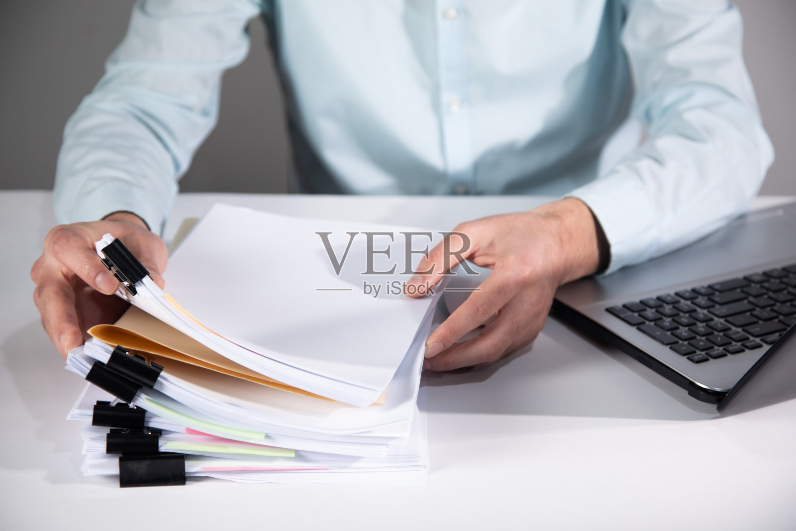 人工作的电脑和成堆的文件照片摄影图片