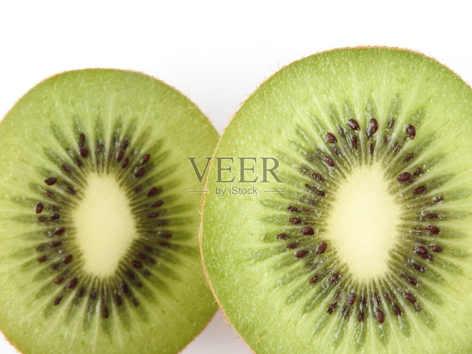 俯视图和接近纹理的成熟新鲜的切片猕猴桃孤立在白色的背景。鲜亮的绿色果肉和可食用的黑色种子。照片摄影图片