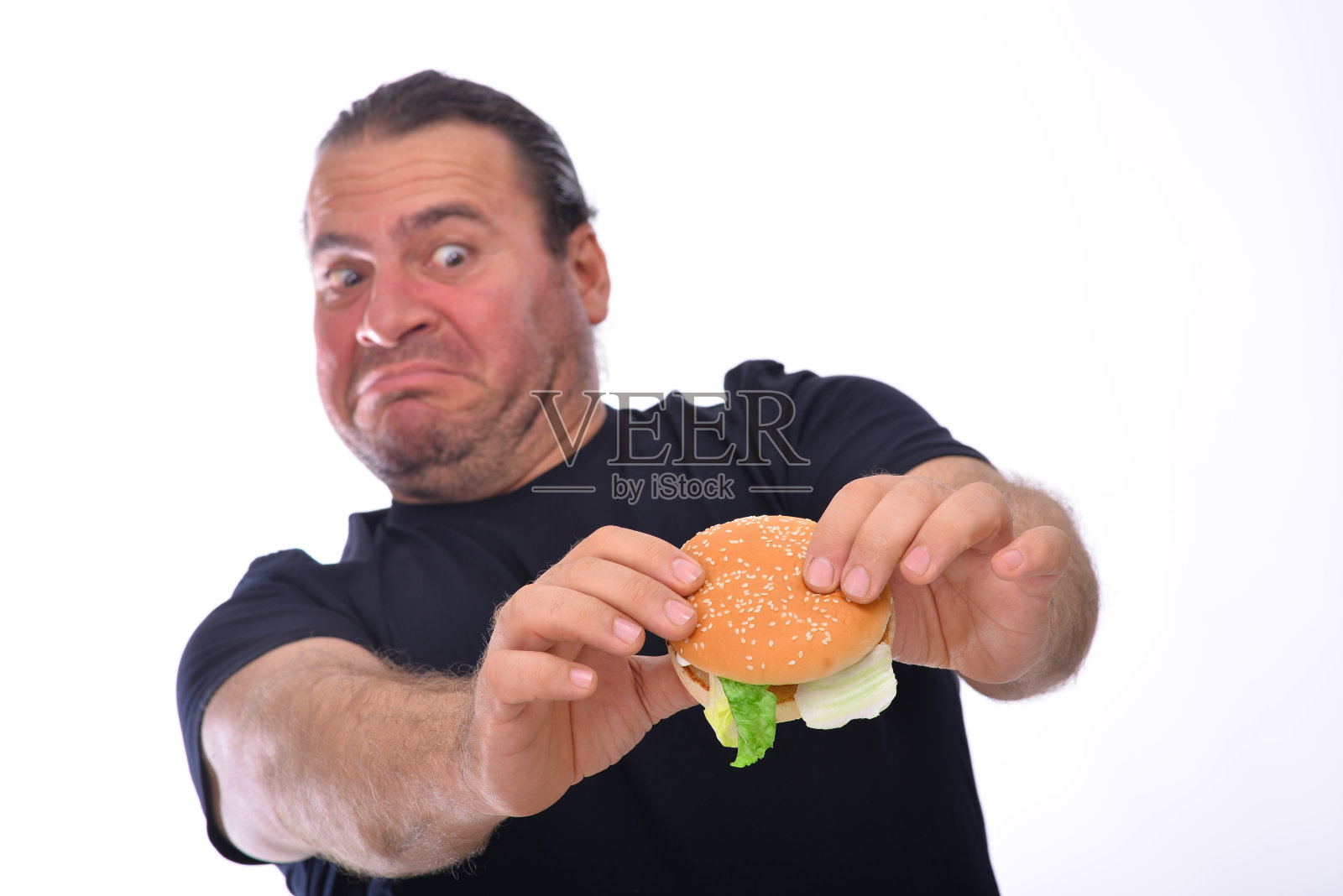 中年男子超重男子盯着汉堡包，准备吃它。照片摄影图片