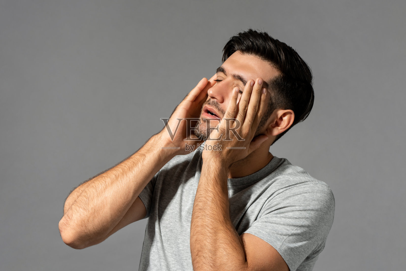 疲劳的年轻白人男子感到头痛，摄影棚拍摄孤立的灰色背景照片摄影图片