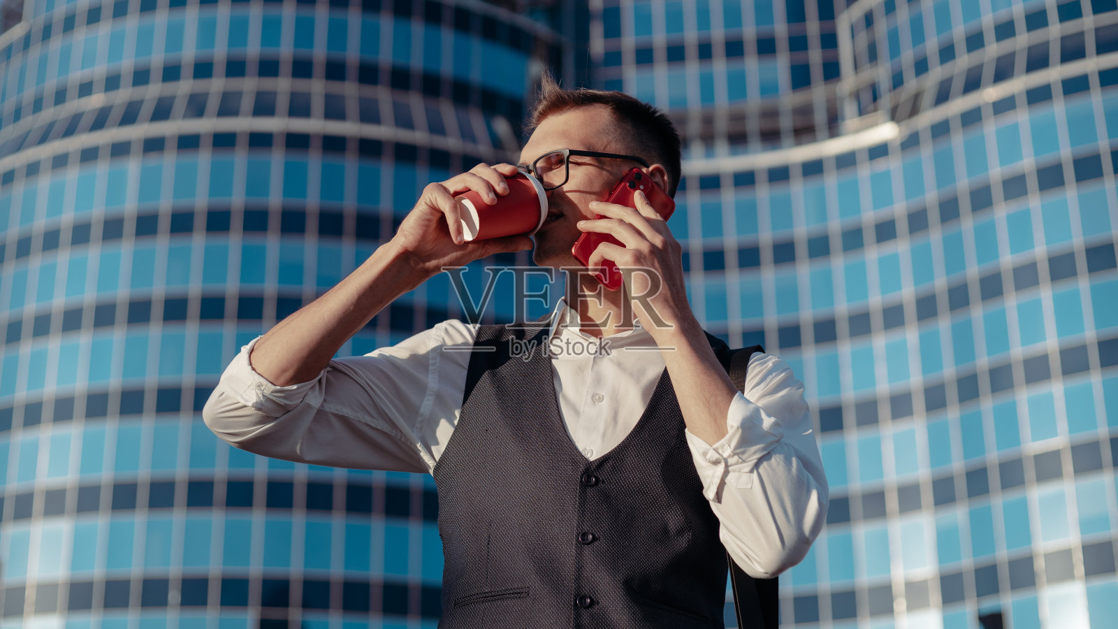 一个年轻人拿着智能手机在一个大办公楼的背景下照片摄影图片