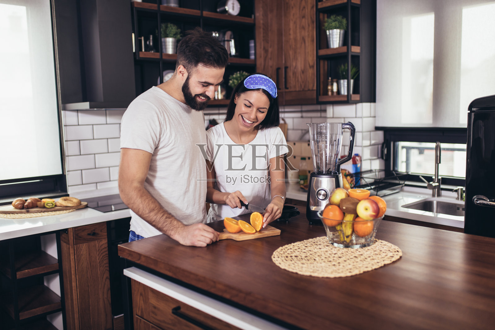 一对相爱的年轻夫妇在家里做早餐。照片摄影图片