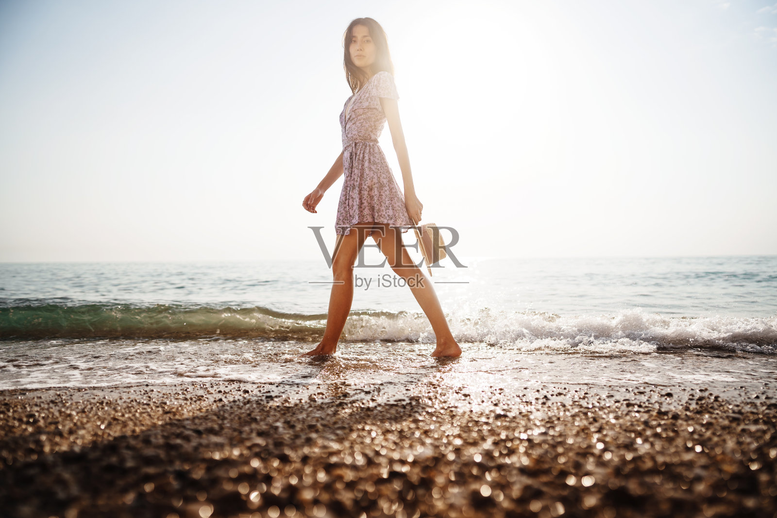 孤独的年轻女子在日落时走在海边照片摄影图片