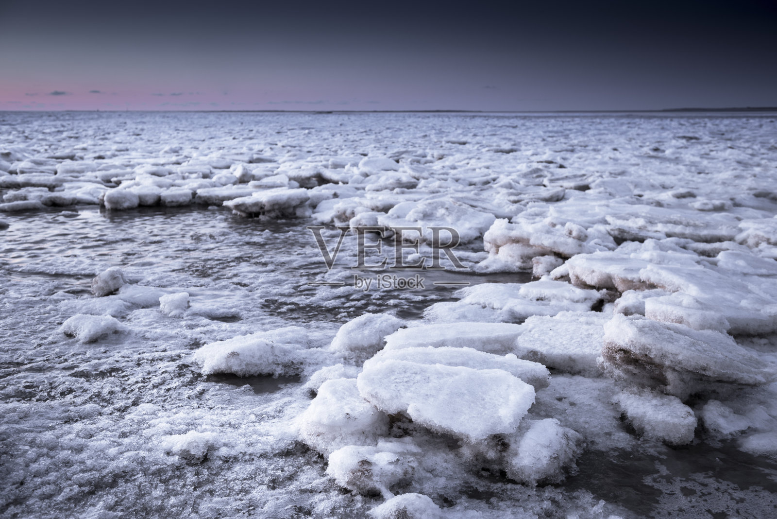 黄昏的时候，波浪状的海面上浮冰照片摄影图片