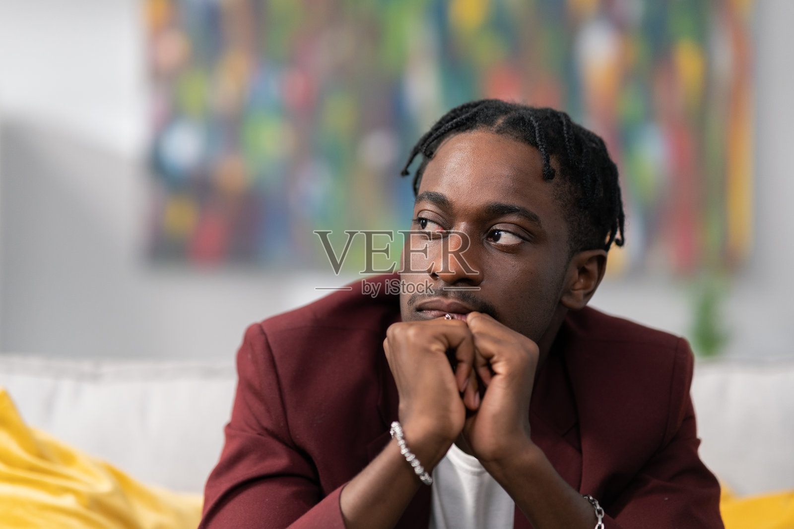 特写商人的脸黝黑的肤色，大公司的员工穿着西装，坐在沙发上，悲伤的双手交缠在下巴下，拼命工作，沮丧的老板照片摄影图片