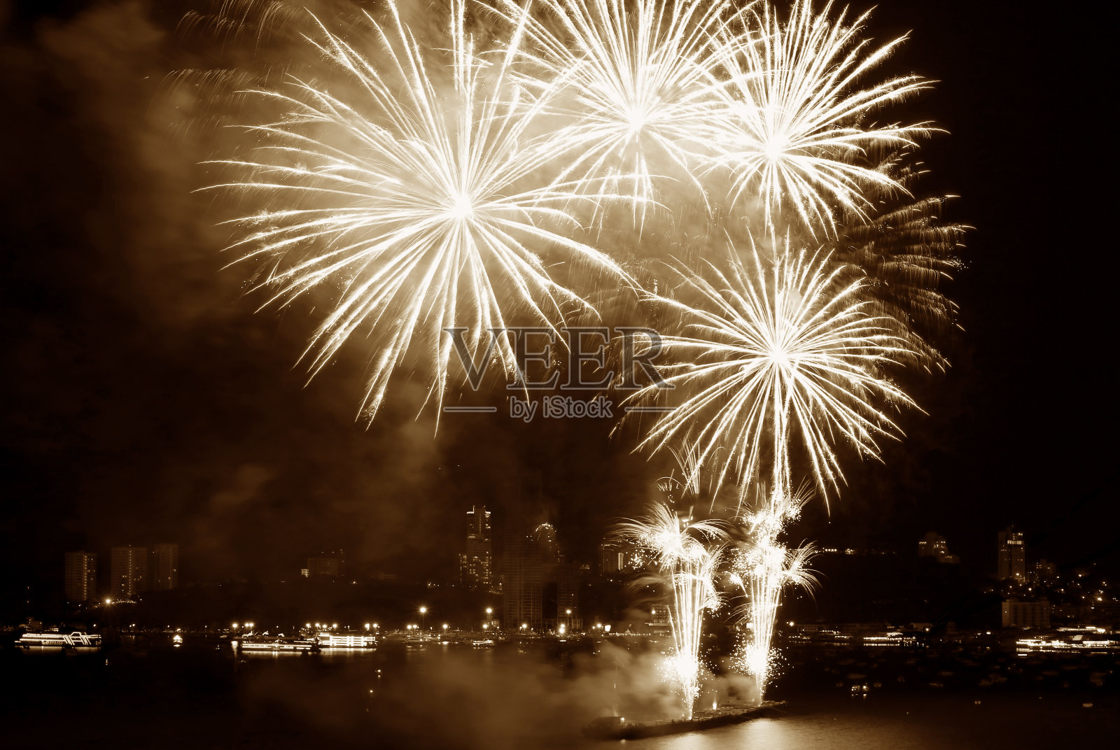 壮观的烟花在夜空中溅起，在棕褐色的海湾上空照片摄影图片