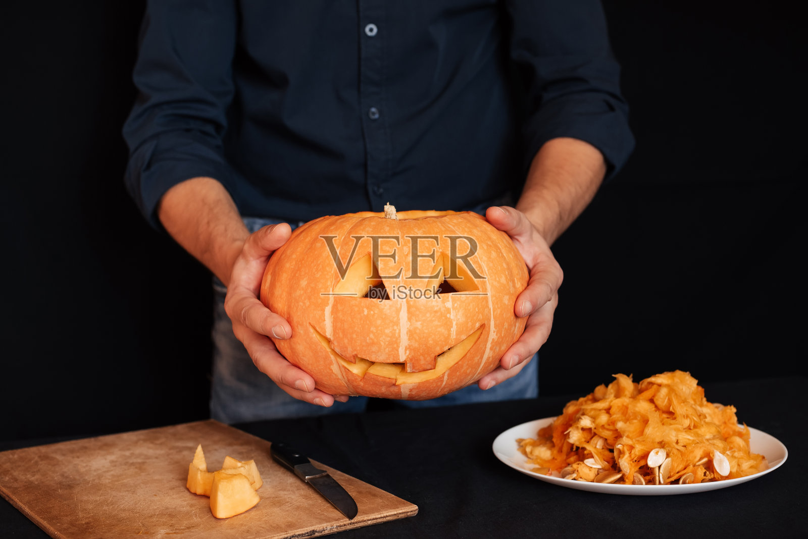 男人手里拿着万圣节用的南瓜照片摄影图片