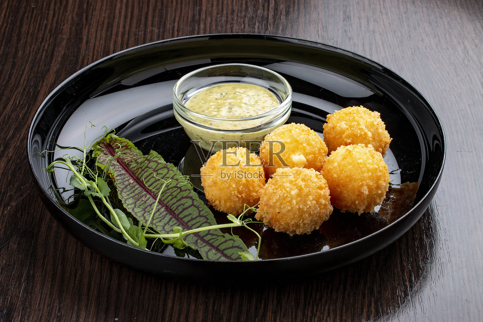 蜂蜜芥末酱奶酪球。在一个光亮的黑色盘子上照片摄影图片