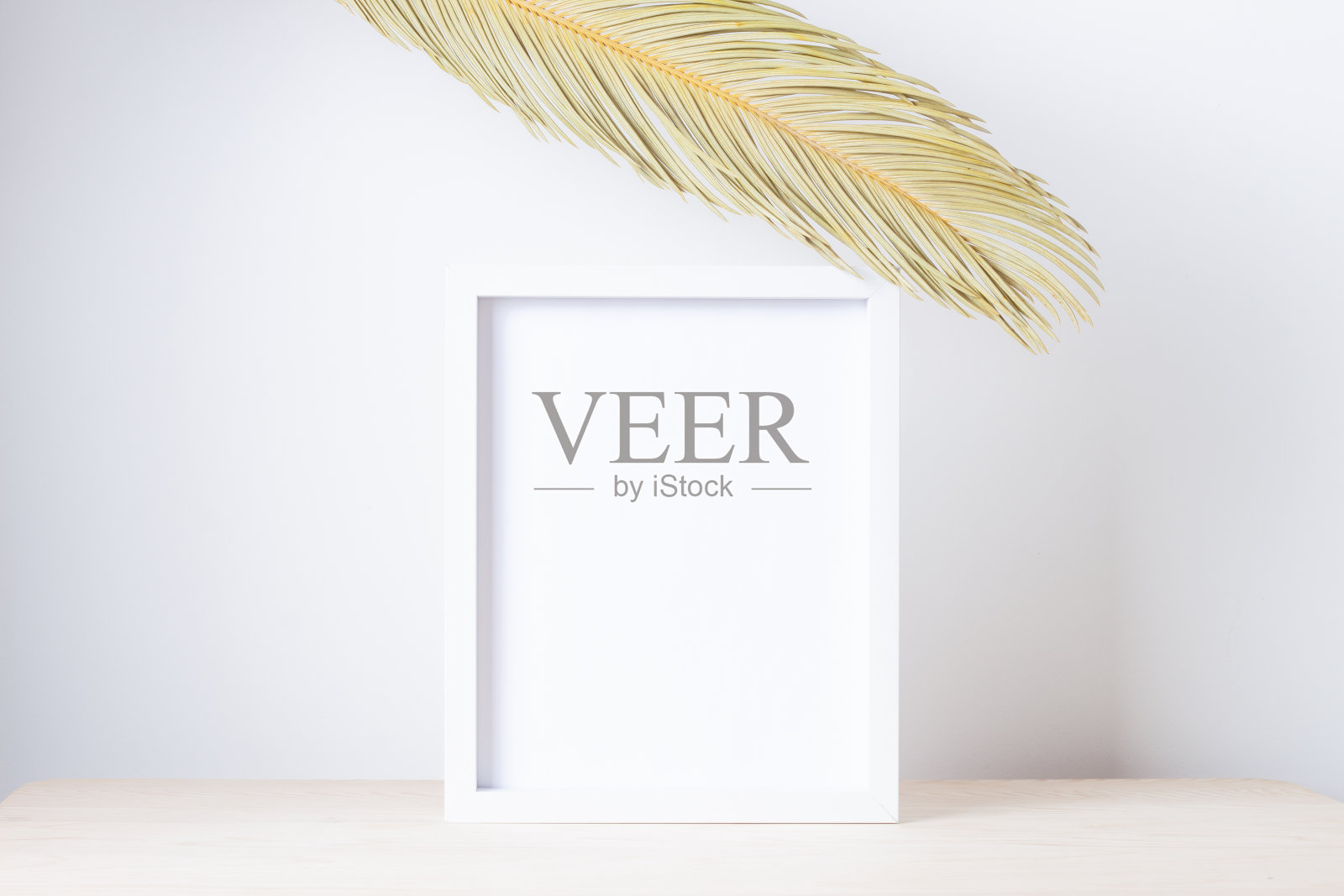 家庭装饰与白色模拟框架和棕榈叶在桌子上。艺术品展示。关闭，复制空间照片摄影图片