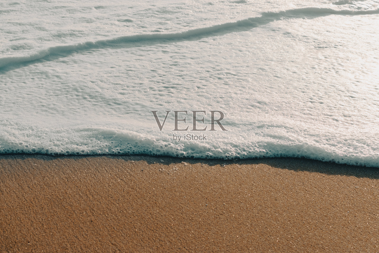 日落时海滩上的海水泛起泡沫。壁纸照片摄影图片