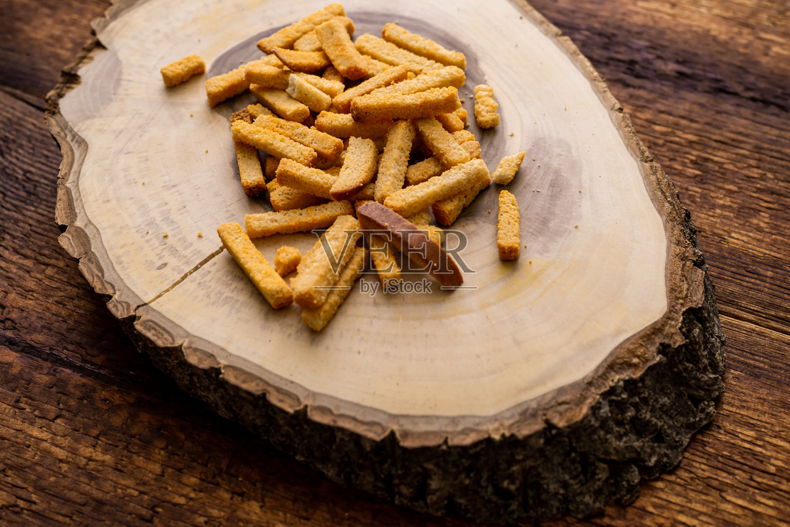 木质背景上的小麦油炸面包丁。在一块木头做的大浅盘上吃零食。照片摄影图片