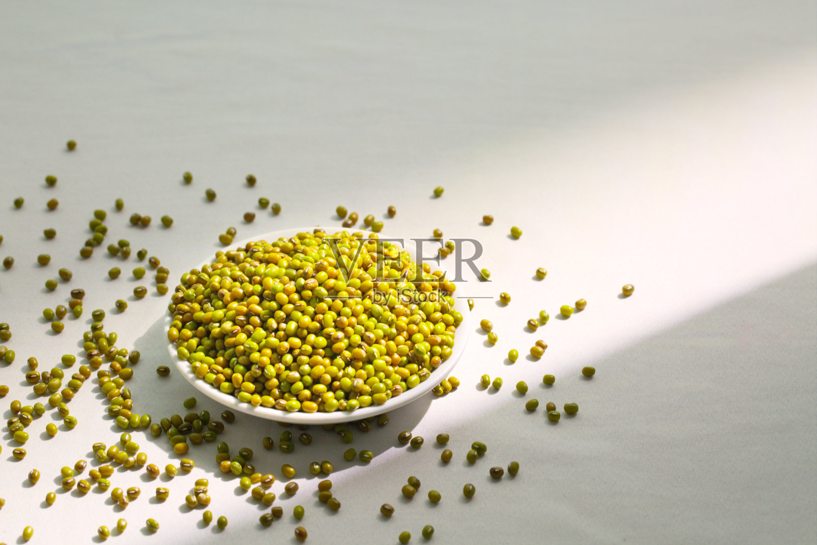 特写一碗绿豆在白色背景上，光影效果，复制空间照片摄影图片