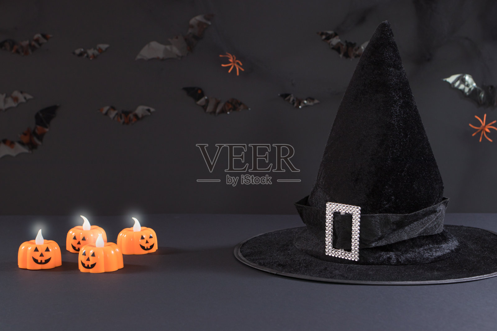 万圣节明信片——黑色背景上有南瓜形状的蜡烛和女巫的帽子，上面有文字。照片摄影图片