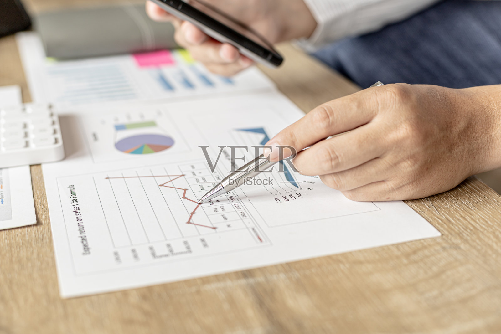 商人在智能手机应用程序中与合作伙伴交谈，他正在检查公司财务数据、财务状况文件的准确性。金融的概念。照片摄影图片