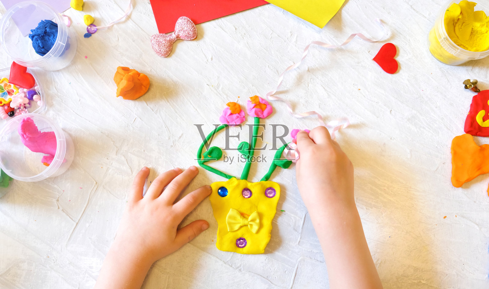 小女孩用五颜六色的泥土、面团、橡皮泥制作鲜花花瓶照片摄影图片