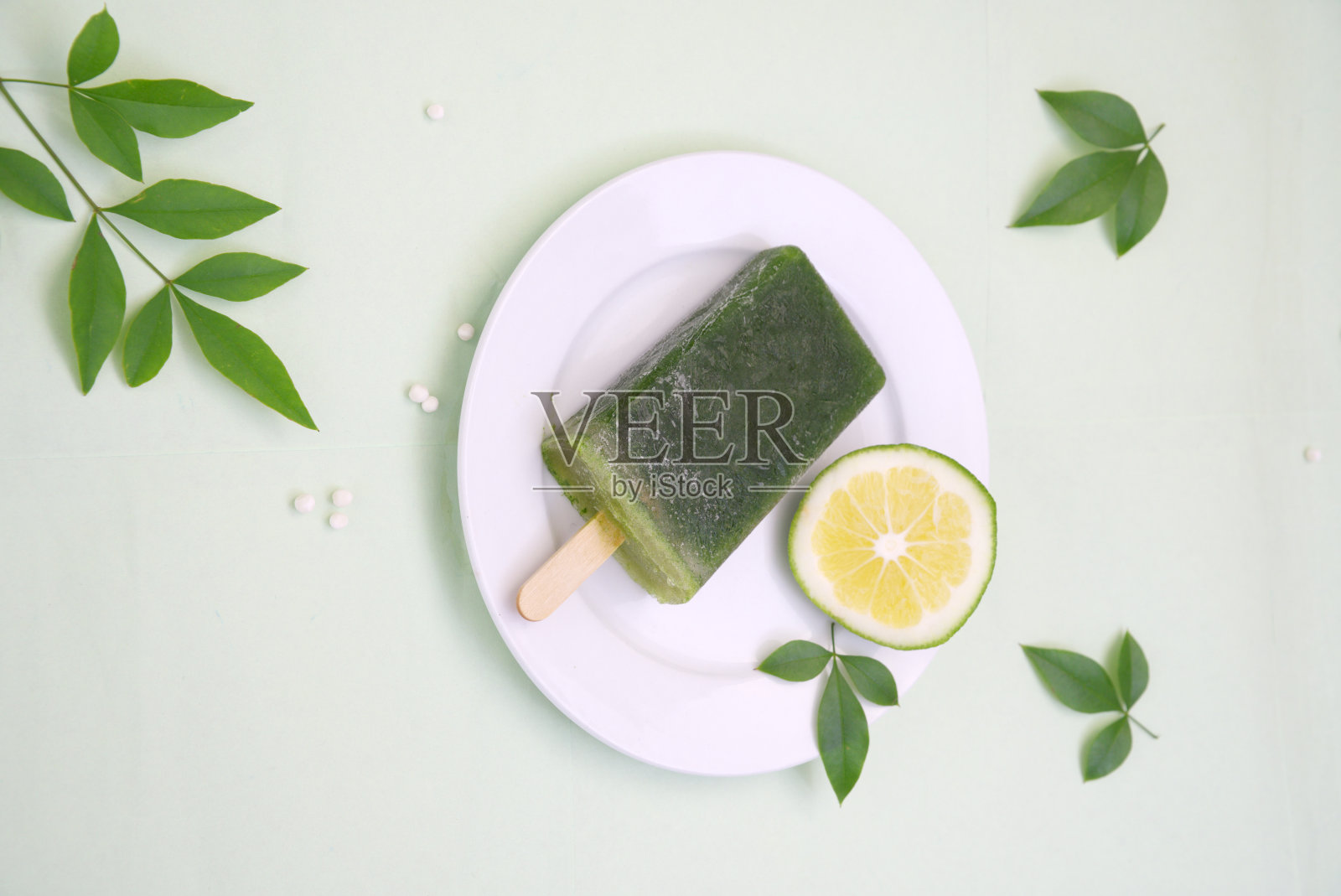 白色盘子上的绿色冰淇淋，绿色的柠檬，绿色的叶子，俯视图照片摄影图片