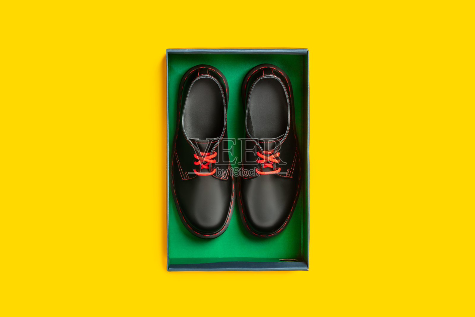 时髦的黑色皮鞋在黄色背景的盒子里，平躺，俯视图照片摄影图片