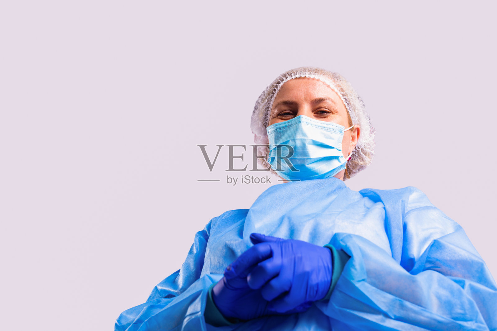 下面的照片中，一名女医生穿着医用大褂，戴着口罩和防护蓝手套，微笑着看着镜头。照片摄影图片