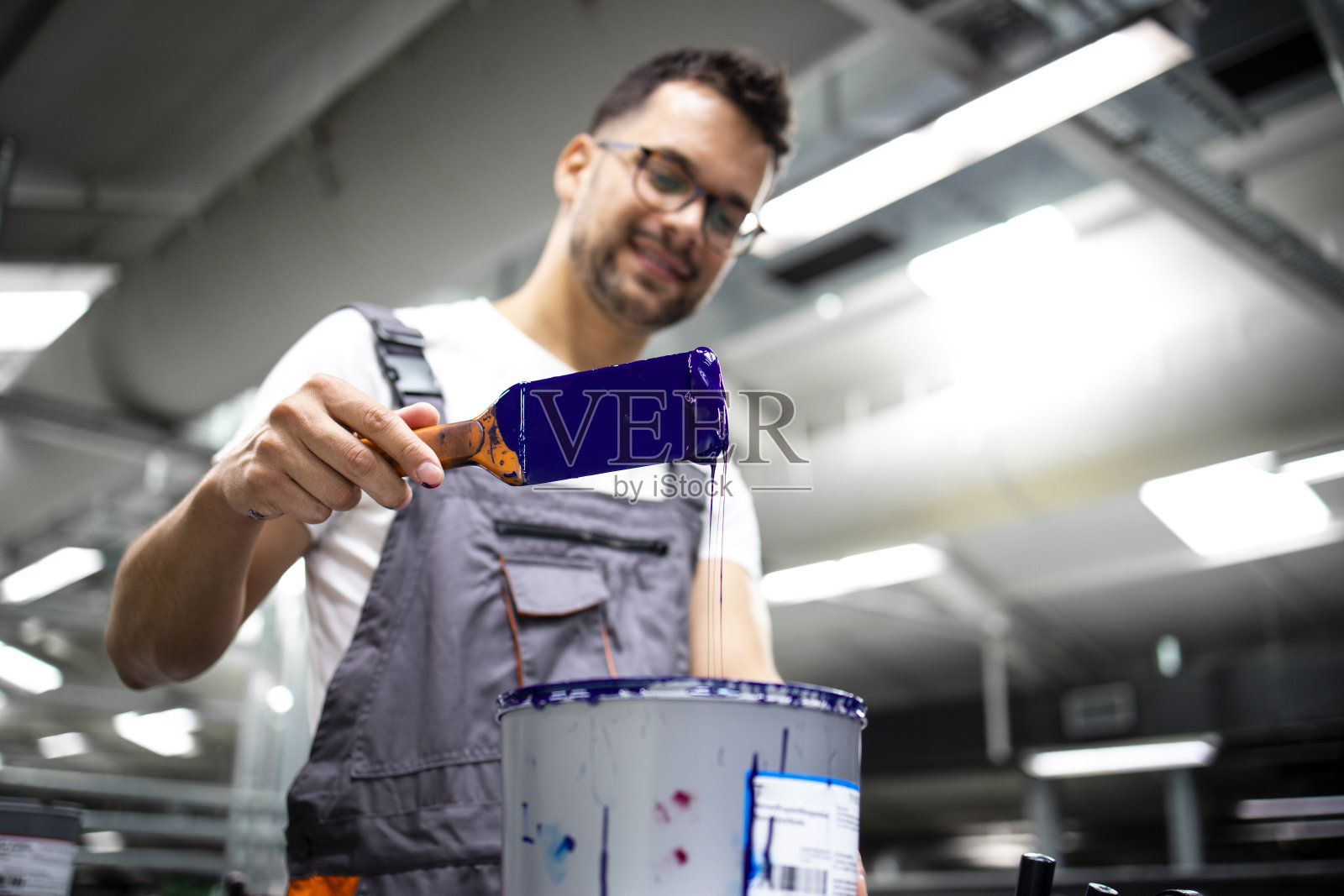 印刷机操作员在给胶印机加色前混合油漆并检查密度。照片摄影图片