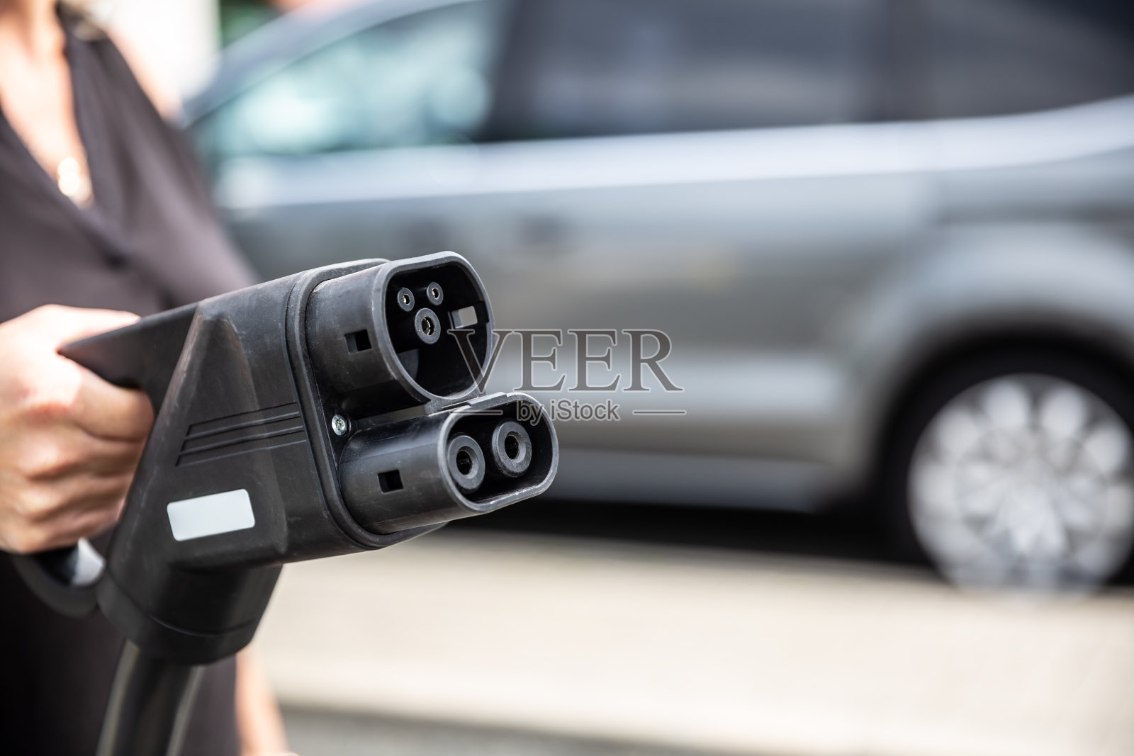 女子手持充电车电缆。照片摄影图片