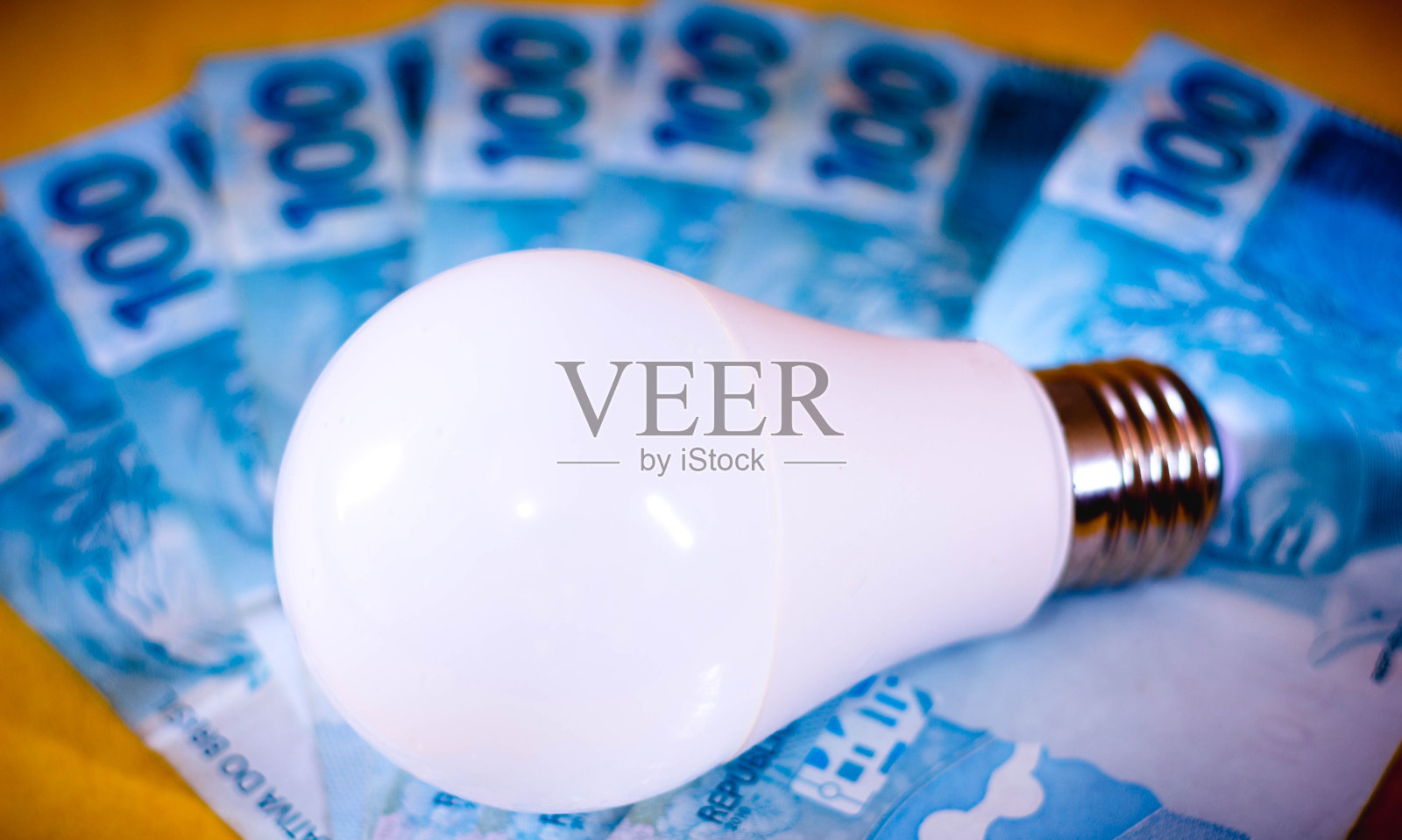 一盏发光二极管(LED)灯照射在几张巴西真钞上。电价的概念。电费照片摄影图片