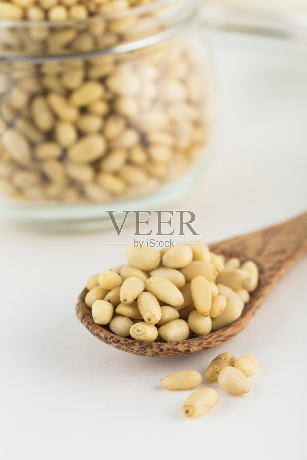 用木勺剥松子，在浅色背景下放入玻璃罐中。照片摄影图片