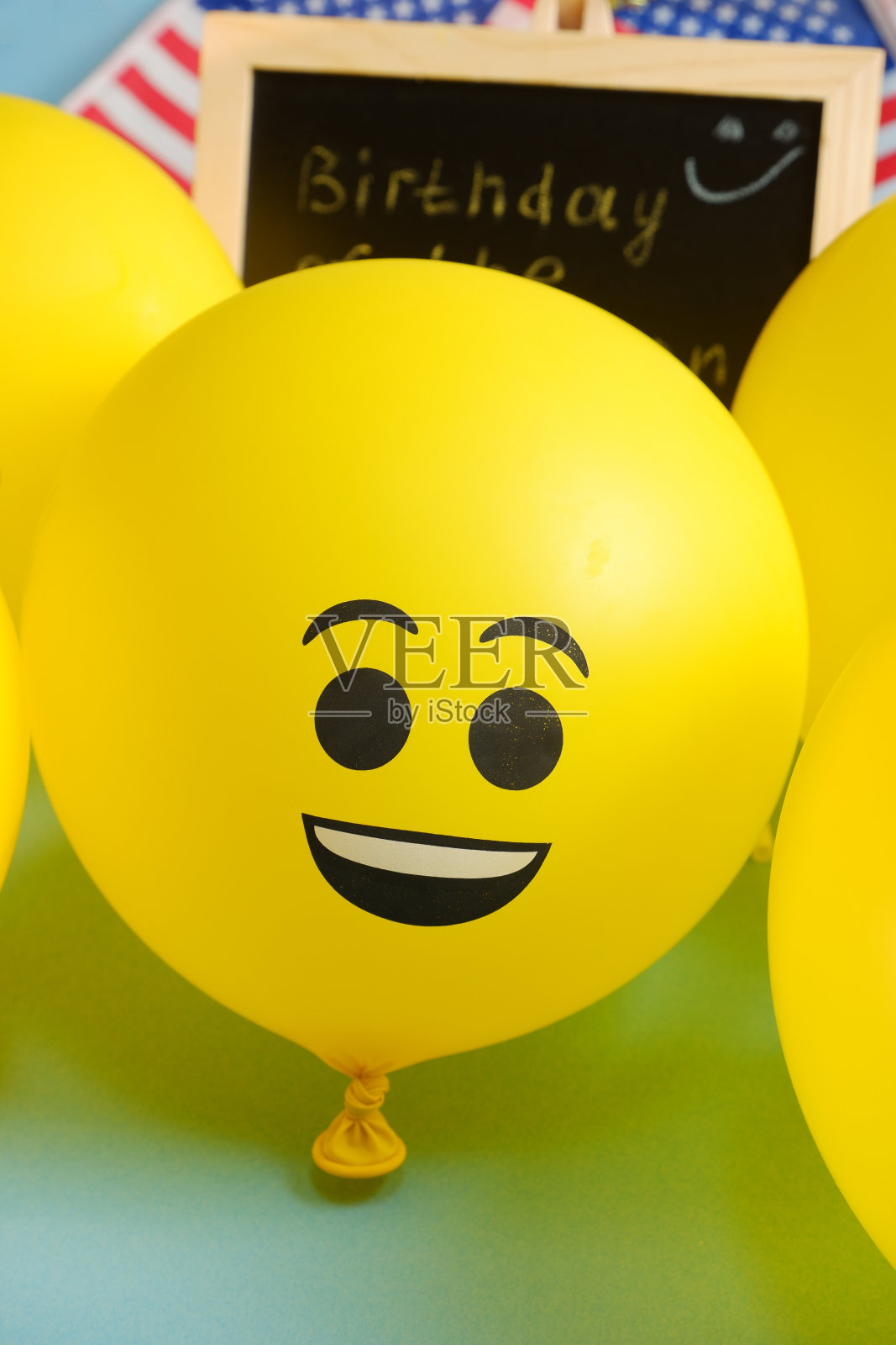 公告板的背景上有黄色的表情符号气球，上面有活动的题词和美国国旗。照片摄影图片