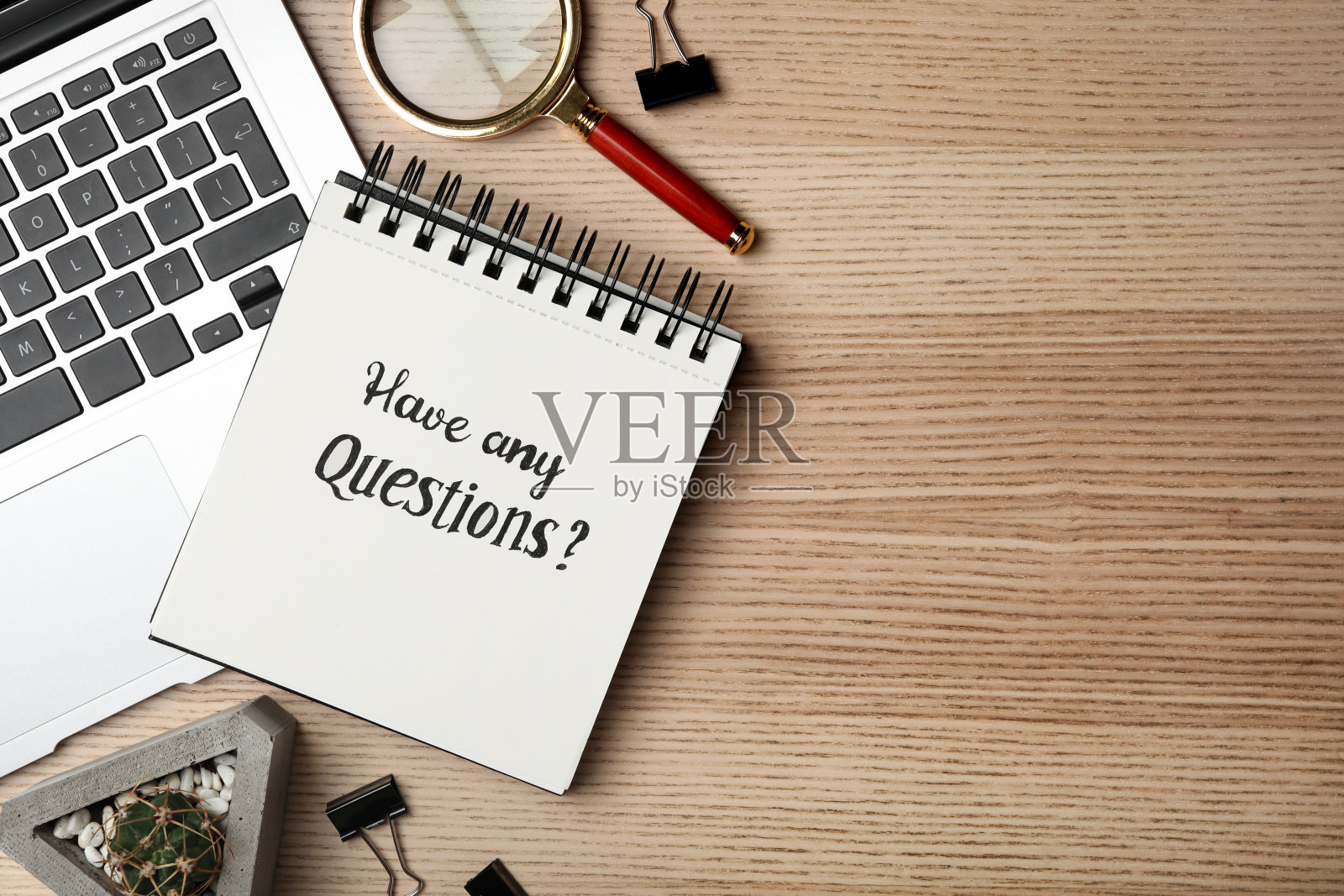 笔记本上写着“有任何问题”，笔记本放在木桌上，平放。空间的文本照片摄影图片