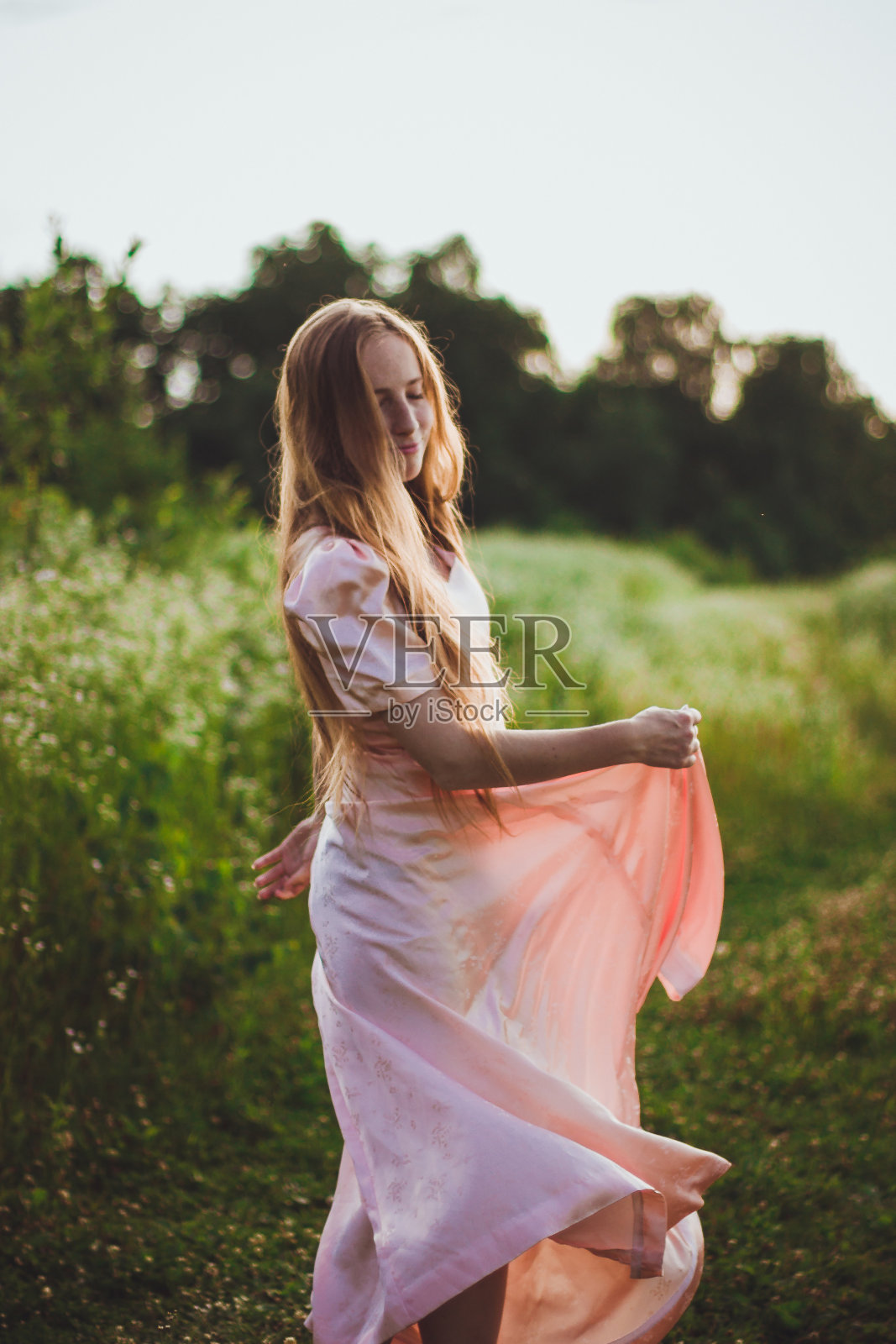 穿着粉红色连衣裙的女孩在田野里跳舞照片摄影图片