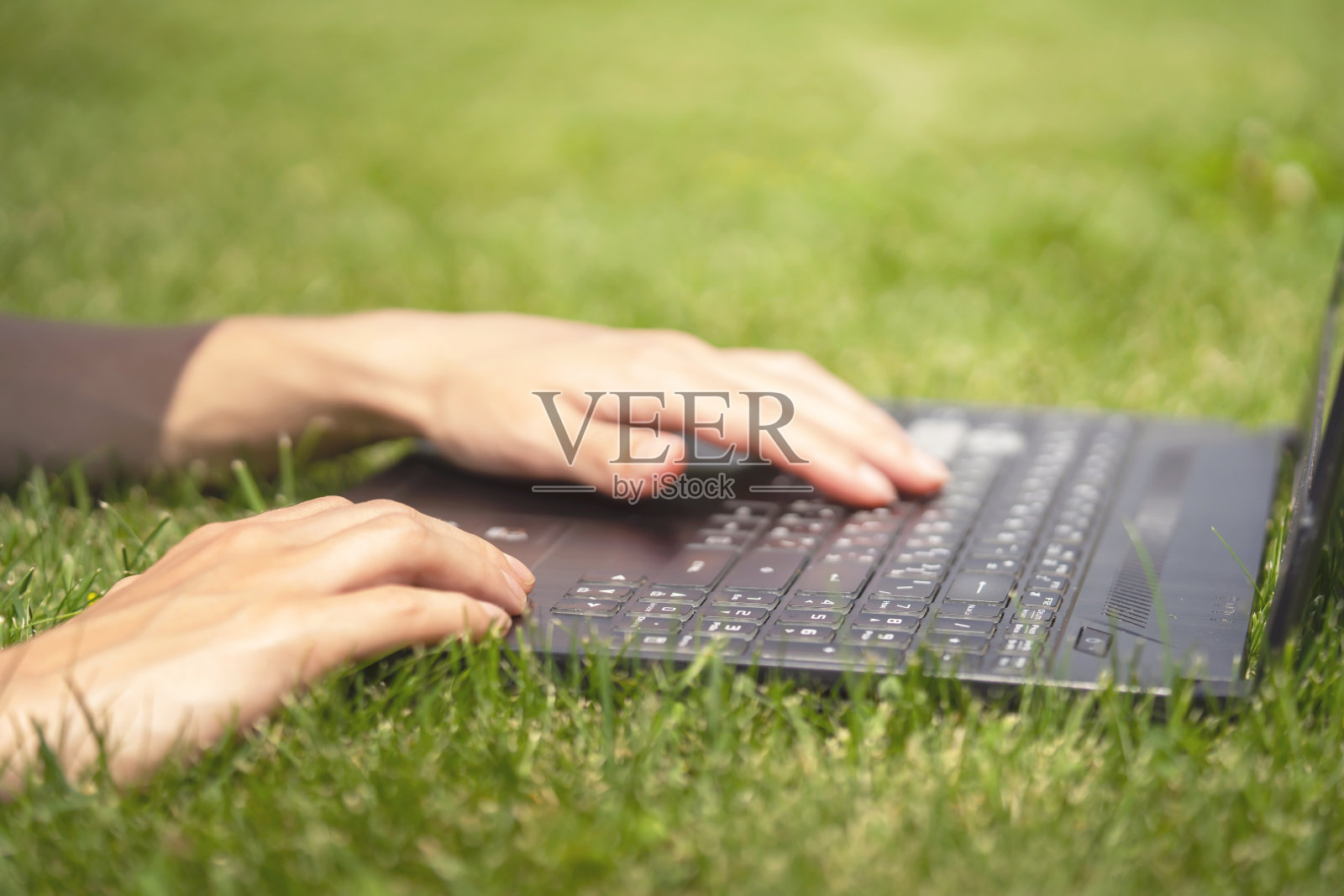 女性的手在笔记本电脑键盘上打字。照片摄影图片