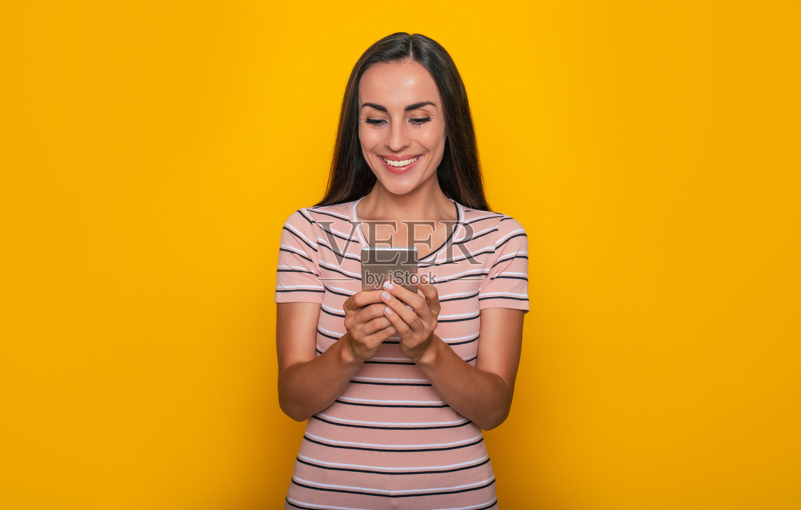 现代美丽的年轻黑发女人正在使用智能手机上网和工作隔离在黄色背景照片摄影图片