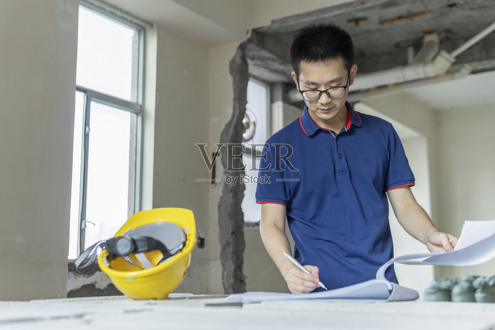 亚洲男性工程师在装修工地处理施工图纸照片摄影图片