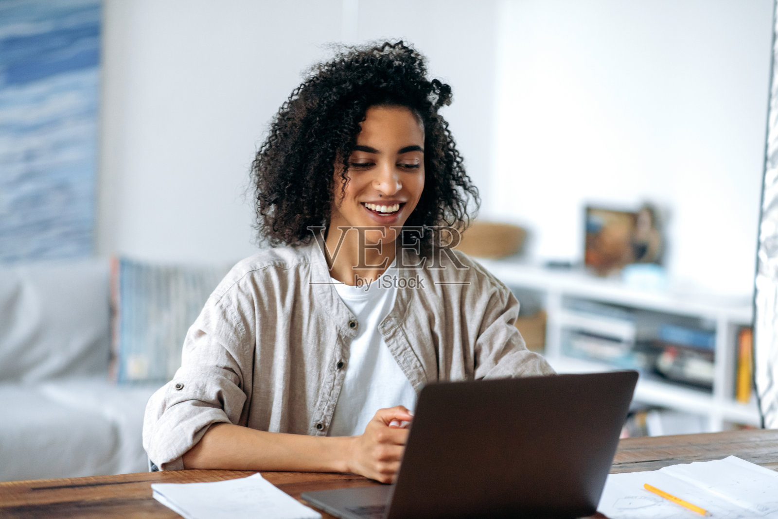 快乐可爱自信的卷发时尚的非洲裔美国女孩，穿着休闲装，经理或学生远程工作，通过视频链接与同事或同学聊天，友好的微笑照片摄影图片