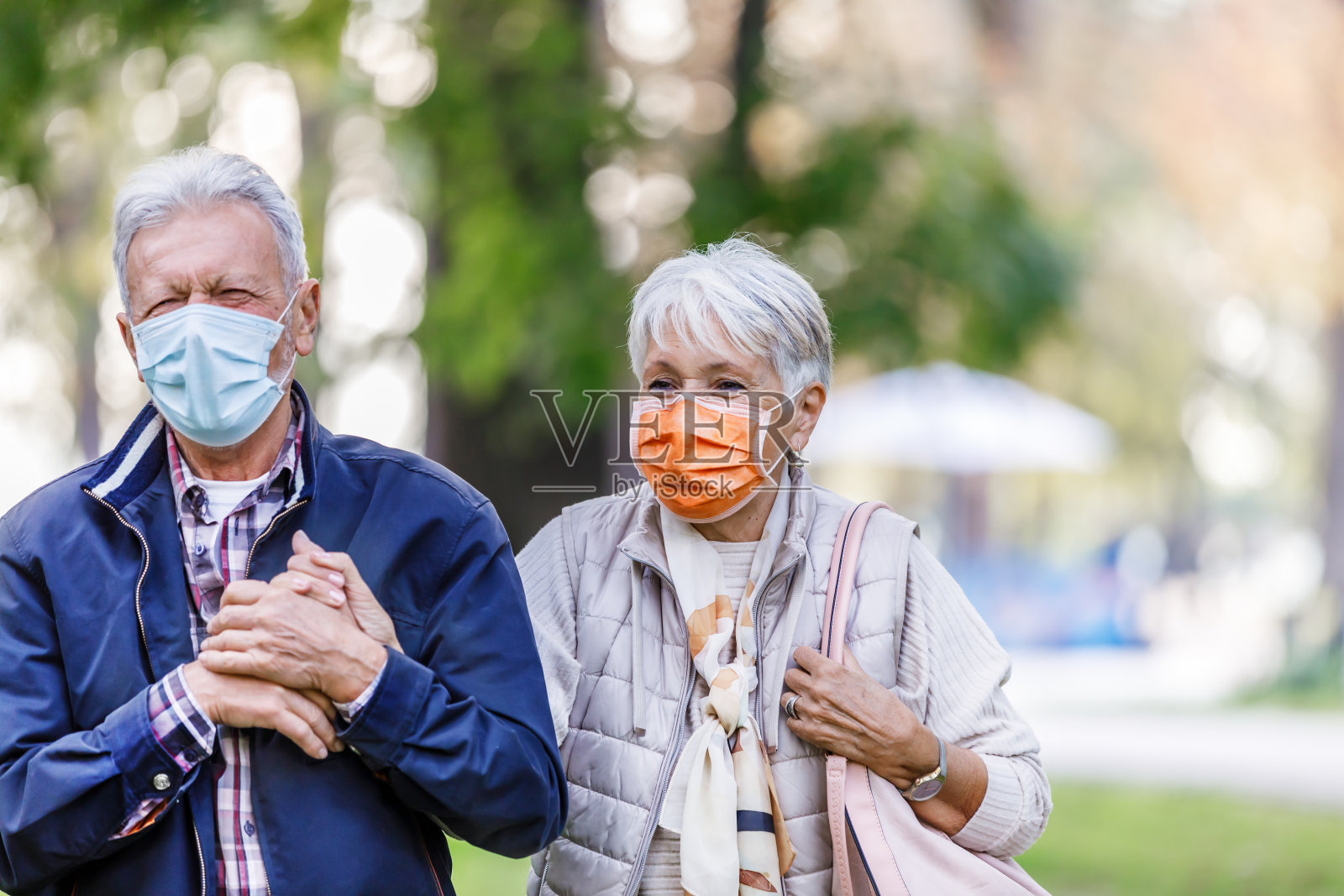 一对戴着口罩的快乐老年夫妇在公园里散步聊天照片摄影图片
