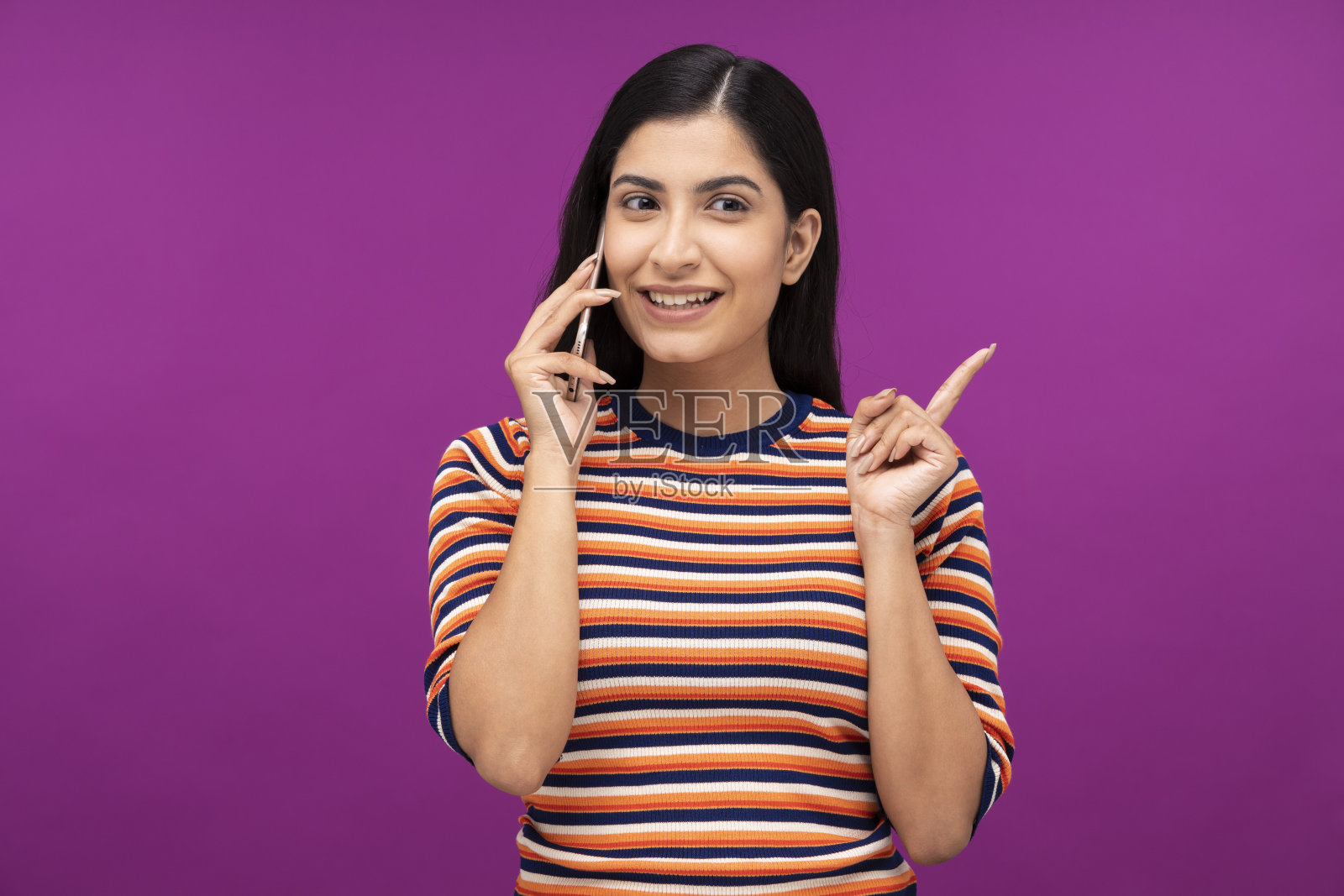 一个年轻女人的肖像在紫色的背景下孤立地站着讲手机照片摄影图片