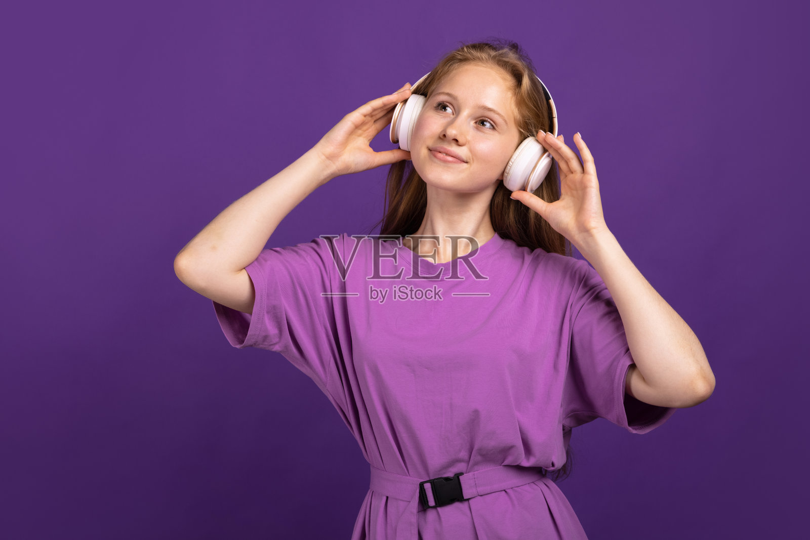 半身像年轻美丽微笑的女孩孤立在紫色的工作室背景。人类情感概念，面部表情，青春，销售，广告。照片摄影图片