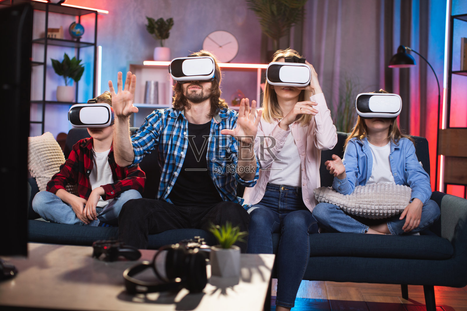 父母带着两个孩子戴着VR眼镜玩游戏照片摄影图片