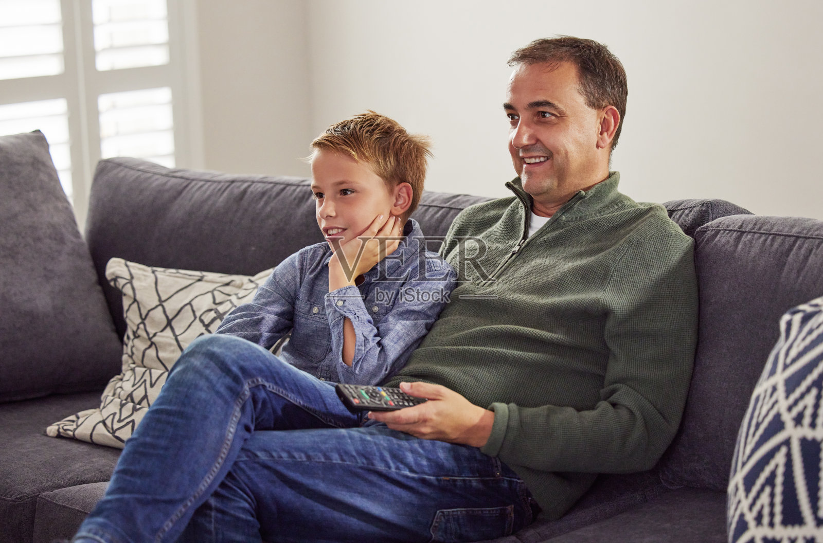 一个英俊成熟的父亲和他的儿子坐在家里的沙发上看电视照片摄影图片