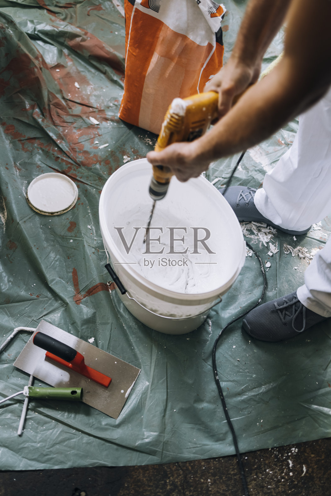 一个匿名男子用油漆搅拌机搅拌桶里的东西照片摄影图片