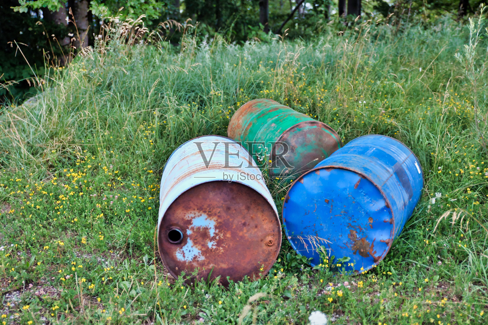 草地上生锈的旧油桶照片摄影图片