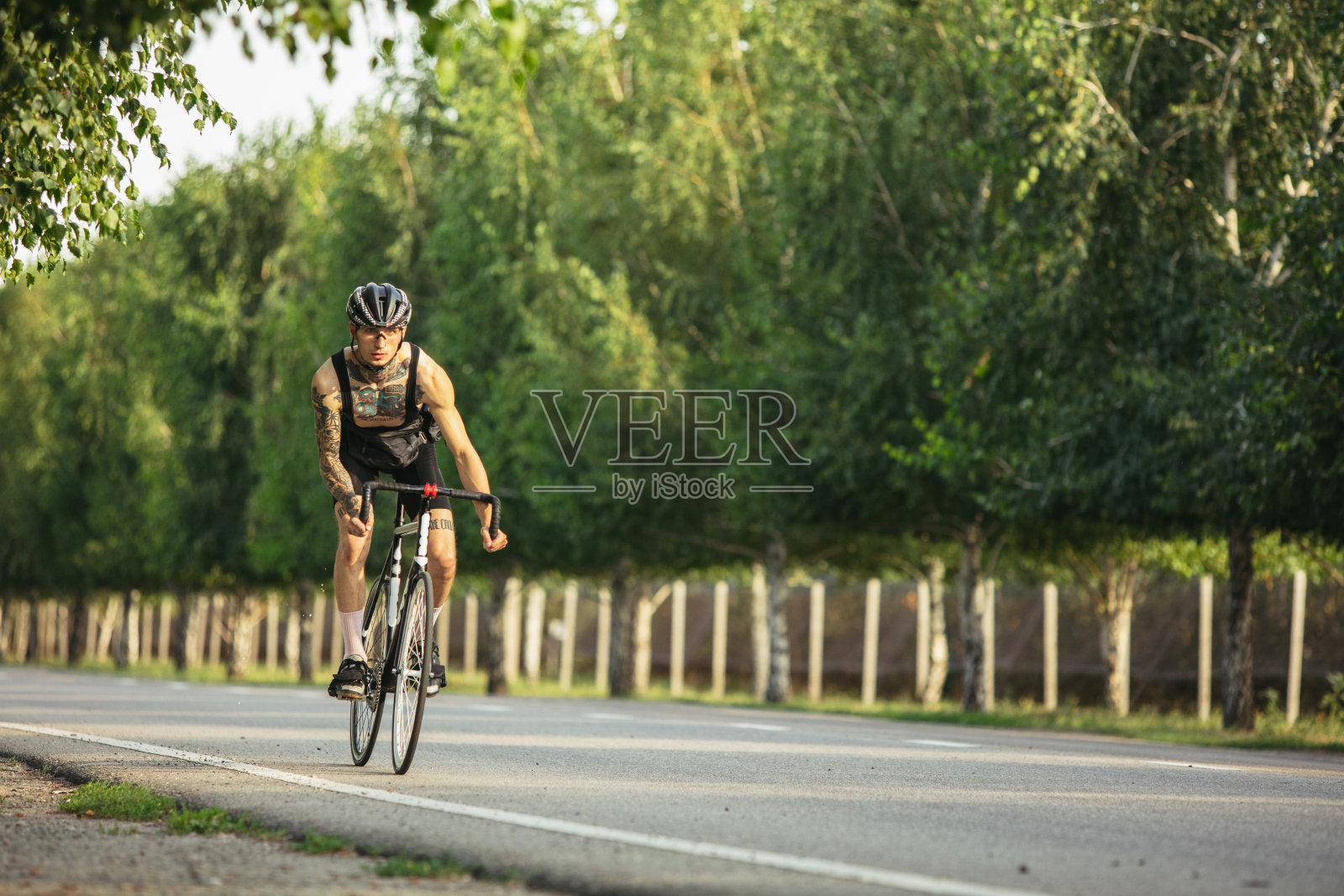 年轻的男性自行车手在夏天骑公路自行车。行动,运动的概念照片摄影图片