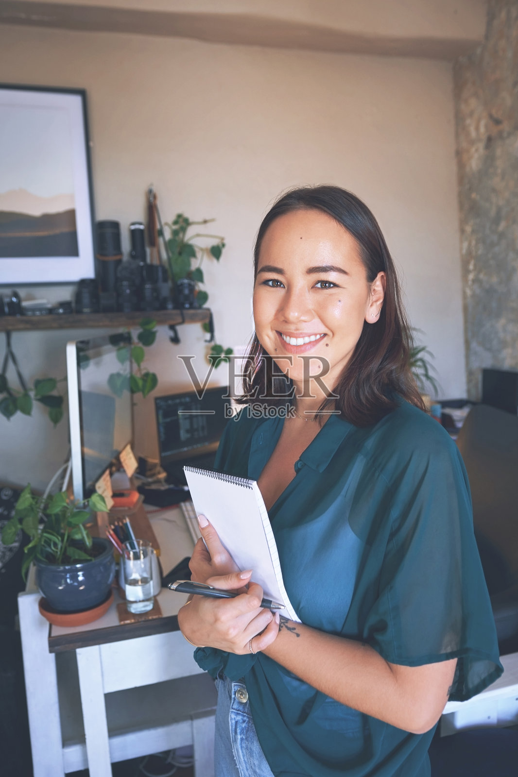 一个漂亮的年轻女人独自站在她的家庭办公室，拿着她的记事本照片摄影图片