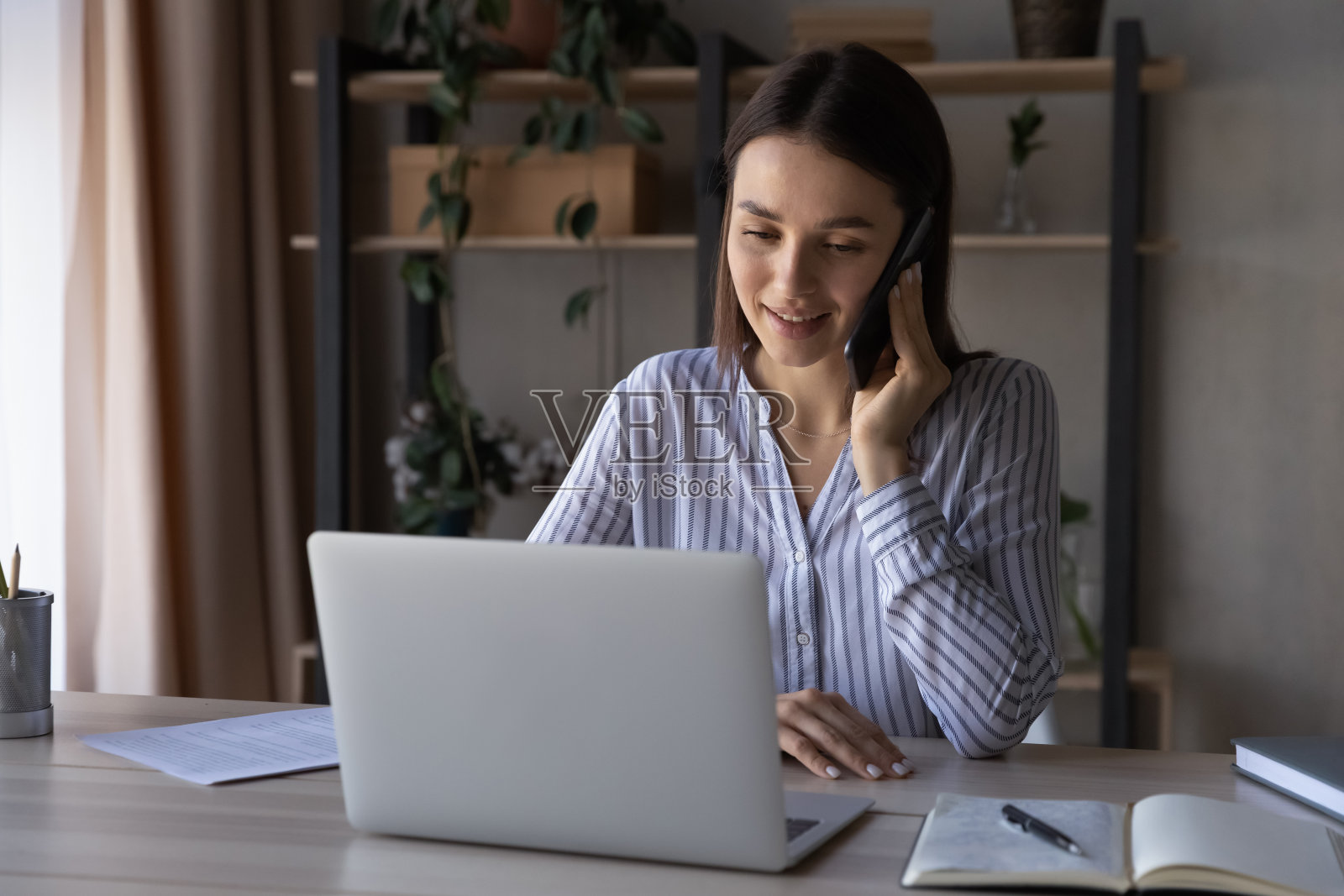 一名年轻的白人女性正在用智能手机进行笔记本通话照片摄影图片