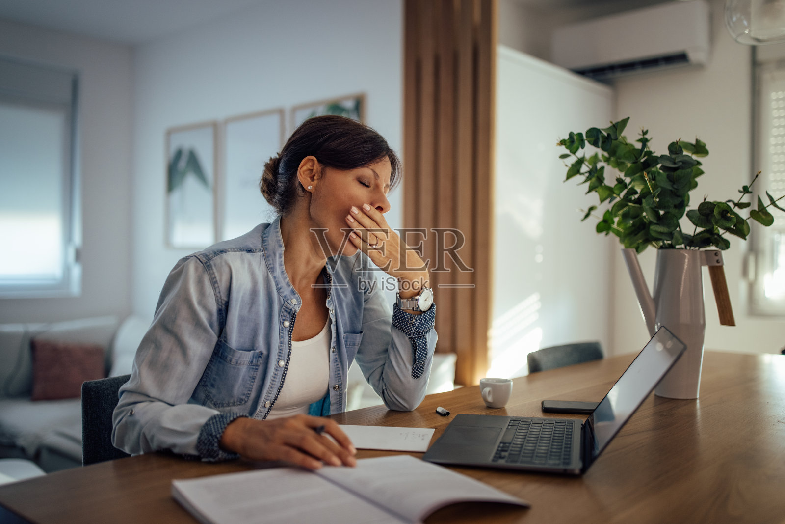 昏昏欲睡的会计加班工作。劳累过度的女人打哈欠。照片摄影图片